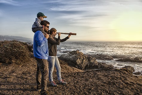 Family with spyglass looking toward ocean