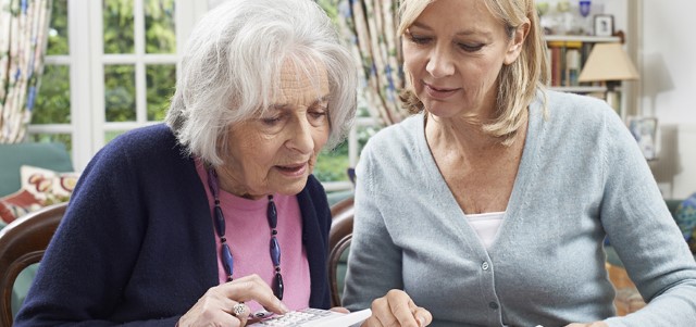 Mature Woman Helping Senior Neighbor With Home Finances