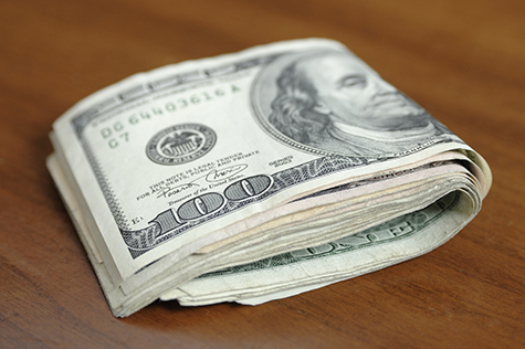 Folded Hundred Dollar Bills on a Wooden Table