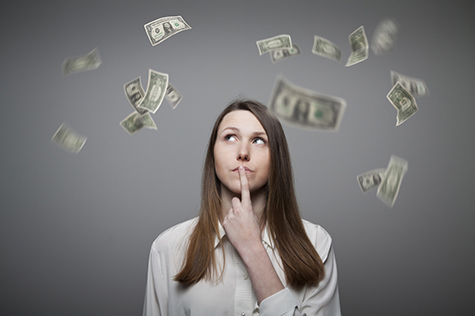 Young woman thinking about dollar bills flying